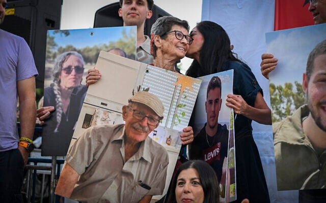 Former hostage Yocheved Lifshitz holds a photo of her husband, Oded, who was killed in Hamas captivity, alongside other bereaved relatives of October 7 victims at the "Sukkah of the Failure" event in Hostages Square, Tel Aviv, during the Jewish holiday of Sukkot, September 28, 2026. (Avshalom Sassoni/Flash90)