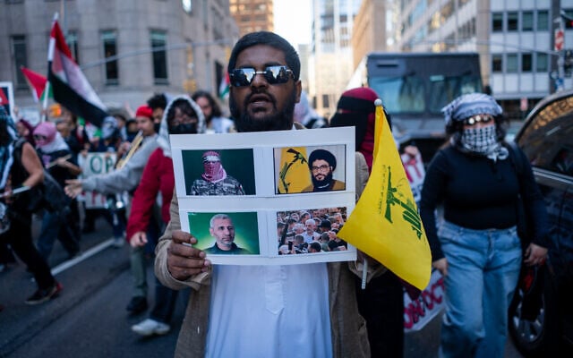 A protester shows Hamas and Hezbollah terrorists, in New York City, October 7, 2026. (Luke Tress/Times of Israel)