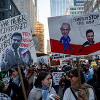 Anti-Zionist protesters hold signs against New York City Mayor Zohran Mamdani, in New York City, October 7, 2026. (Luke Tress/Times of Israel)