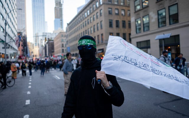 A man in a Hamas headband, holding a Hamas flag, at an anti-Zionist protest,\ in New York City, October 7, 2026. (Luke Tress/Times of Israel)