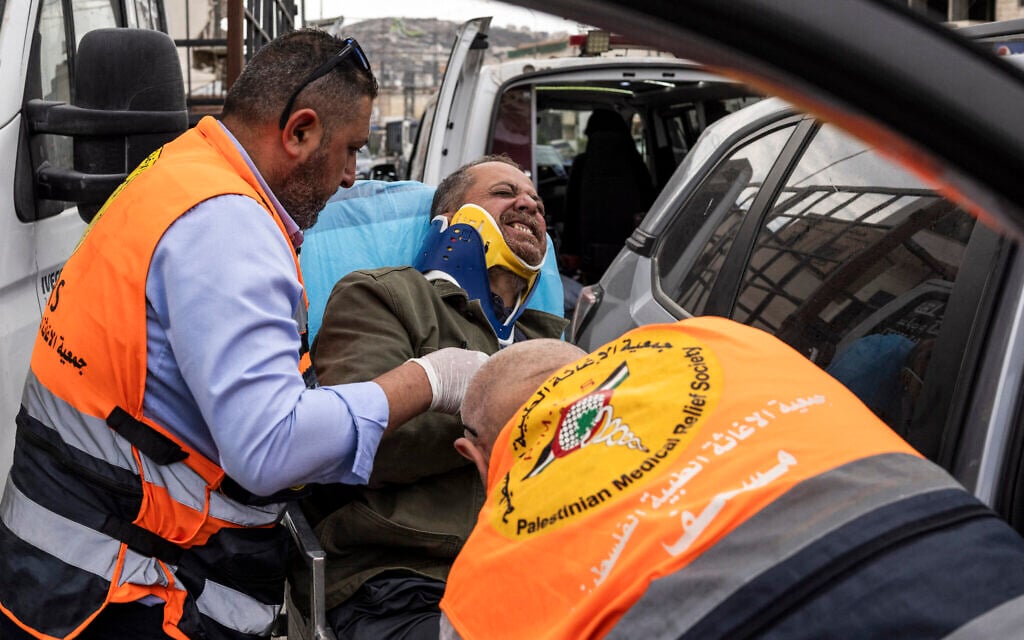 Agence France-Presse’s (AFP) photographer Jaafar Ashtiyeh is carried by Palestinian first responders to seek medical assistance after being beaten by several Israelis in Aqraba in the West Bank on October 6, 2026. (JOHN WESSELS/AFP)