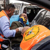 Agence France-Presse’s (AFP) photographer Jaafar Ashtiyeh is carried by Palestinian first responders to seek medical assistance after being beaten by several Israelis in Aqraba in the West Bank on October 6, 2026. (JOHN WESSELS/AFP)