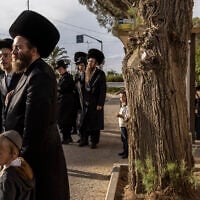 Ultra-Orthodox Jews wait at a bus stop in Arad on October 1, 2026. (JOHN WESSELS/AFP)