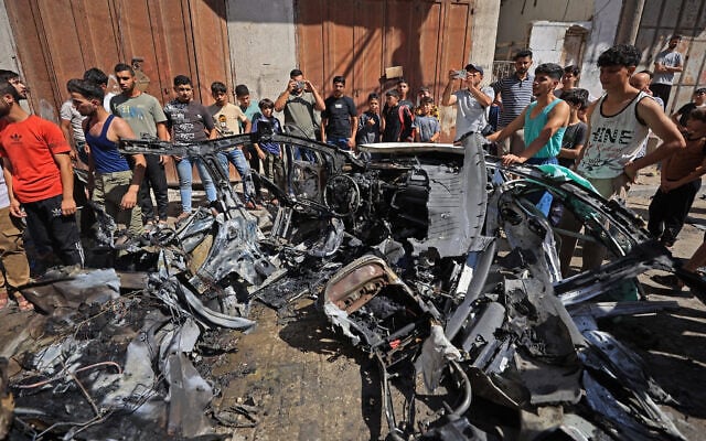 Palestinians inspect the wreckage of a car after it was destroyed in an Israeli strike at the Tuffah neighborhood of Gaza City on October 13, 2026. (Omar AL-QATTAA/AFP)