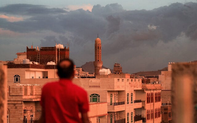A man looks on as a minaret soars over the skyline of a neighborhood, pictured at sunset in Yemen’s Houthi-controlled capital Sanaa on October 13, 2026. (Mohammed HUWAIS/AFP)