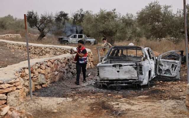 Palestinian volunteers pack hose pipes used to douse an olive tree reportedly set alight, along with Palestinian-owned vehicles, by Israeli settlers near the village of Turmus Ayya, north of the city of Ramallah in the West Bank on October 16, 2026. (AHMAD GHARABLI/AFP)