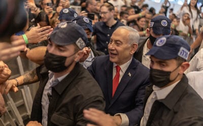 Prime Minister Benjamin Netanyahu stands amid security personnel as he meets with voters at a mall in Ramle on October 19, 2026. (ilia YEFIMOVICH/AFP) Prime Minister Benjamin Netanyahu stands amid security personnel as he meets with voters at a mall in Ramle on October 19, 2026. (ilia YEFIMOVICH/AFP)