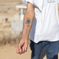 Danny, a resident of Kibbutz Nahal Oz, shows his black-ink sunflower forearm tattoo with a Hebrew script reading “The Way to Hope," which he had to commemorate the memory of Hamas’s October 7, 2023, onslaught, in Nahal Oz in southern Israel on October 22, 2026. (Ilia YEFIMOVICH/AFP)