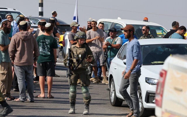 Settlers at the scene of gun battle between troops and two Palestinians who opened fire at a checkpoint near Hebron in the West Bank on October 23, 2026. (Ahmad GHARABLI/AFP)