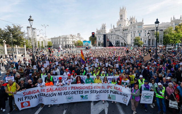 Protesters hold banners and flags during a demonstration calling for an increase to pensions and wages through central Madrid on October 24, 2026. (Oscar DEL POZO/AFP) Protesters hold banners and flags during a demonstration calling for an increase to pensions and wages through central Madrid on October 24, 2026. (Oscar DEL POZO/AFP)