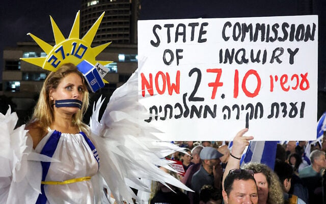 A protester wearing a closed zipper on her mouth and a costume while draped in the Israeli flag poses during an anti-government demonstration at Hostages Square in Tel Aviv on October 24, 2026, several days before general elections. (Jack Guez/AFP)