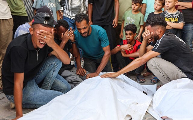 Mourners grieve next to the bodies of three Palestinians during their funeral at Al-Shifa Hospital in Gaza City on October 25, 2026, after they were reportedly killed in an Israeli strike on the Islamic University building. (Omar AL-QATTAA/AFP)