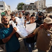 Mourners carry the body of one of three Palestinians during their funeral at Shifa Hospital in Gaza City on October 25, 2026, after they were killed in an Israeli strike on the Islamic University building. (Omar AL-QATTAA/AFP)