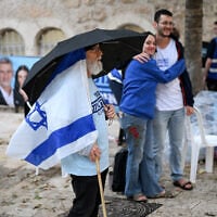 A volunteer stands under an umbrella in the rain outside a polling station in Jerusalem on October 27, 2026, on election day. (Jewel SAMAD/AFP)
