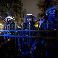 Police officers stand behind the fence with a rosary hanging on it as protesters gather outside the headquarters of Poland’s Constitutional Court in Warsaw after police blocked access to the court building on October 30, 2026. (Wojtek RADWANSKI/AFP)