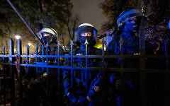 Police officers stand behind the fence with a rosary hanging on it as protesters gather outside the headquarters of Poland’s Constitutional Court in Warsaw after police blocked access to the court building on October 30, 2026. (Wojtek RADWANSKI/AFP)