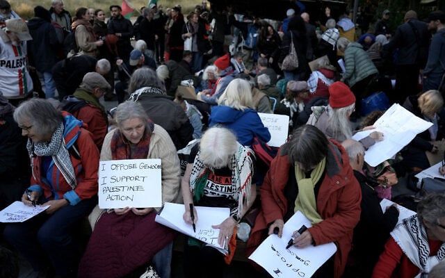 Pro-Palestinian, anti-Israel activists and supporters write on placards during a protest in support of Palestine Action, which the UK government has proscribed as a terror group, outside the US Embassy in London on October 31, 2026. (Carlos Jasso/AFP)