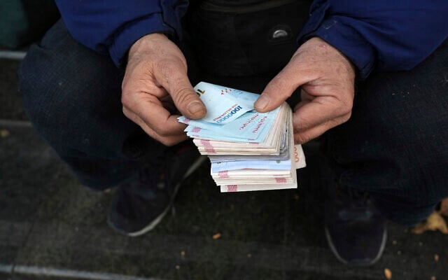 A street money exchanger poses for a photo without showing his face as he counts Iranian banknotes at a commercial district in downtown Tehran, Iran, December 23, 2022. (Vahid Salemi/AP) A street money exchanger poses for a photo without showing his face as he counts Iranian banknotes at a commercial district in downtown Tehran, Iran, December 23, 2022. (Vahid Salemi/AP)