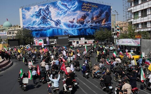 Motorcyclists drive past a billboard depicting a Persian legendary hero and flying figure hitting US aircraft carriers alongside the message in English and Farsi: “From the Persian Gulf a new power rises,” “The army of Satan will be drowned in the Persian Gulf," during a state-organized motorcycle parade called “Janfada,” meaning “Sacrifice for Iran,”, in Tehran, Iran, September 25, 2026. (AP Photo/Vahid Salemi)