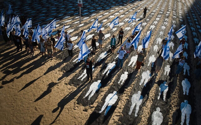 People carrying Israeli flags walk through an installation marking the third anniversary of the October 7, 2023, Hamas attack on Israel, on the beachfront in Tel Aviv, Israel, October 7, 2026. (AP Photo/Oded Balilty)
