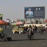 Motorists and street vendors pass by billboards bearing images of Houthi leader Abdul Malik al-Houthi, right, and the late Hezbollah leader Hassan Nasrallah in Sanaa, Yemen, October 8, 2026. (AP Photo/Osamah Abdulrahman)