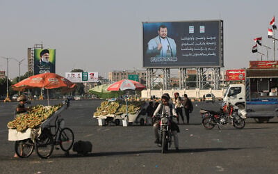 Motorists and street vendors pass by billboards bearing images of Houthi leader Abdul Malik al-Houthi, right, and the late Hezbollah leader Hassan Nasrallah in Sanaa, Yemen, October 8, 2026. (AP Photo/Osamah Abdulrahman)