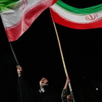 Demonstrators wave Iranian flags during a pro-government gathering at a square in Tehran, Iran, October 8, 2026. (AP Photo/Vahid Salemi)