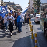 Supporters of Prime Minister Benjamin Netanyahu walk alongside a bus displaying a campaign poster featuring his chief rival, Gadi Eisenkot, at Jerusalem’s Mahane Yehuda market, ahead of Israel’s general election, October 9, 2026. (AP Photo/Ohad Zwigenberg)