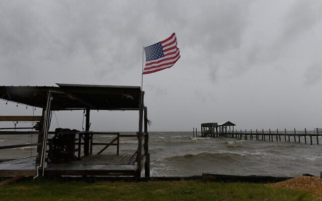 A US flag flaps in the wind generated by Hurricane Isaias on an empty beach on Mon Louis Island, Alabama, on October 9, 2026 (AP Photo/Octavio Jones)