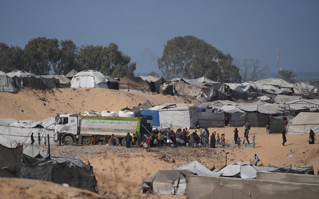 Displaced Palestinians gather to fill containers with fresh water from a supplier in Deir al-Balah, central Gaza Strip, October 10, 2026. (AP Photo/Abdel Kareem Hana)