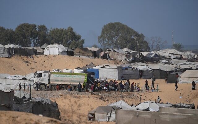 Displaced Palestinians gather to fill containers with fresh water from a supplier in Deir al-Balah, central Gaza Strip, October 10, 2026. (AP Photo/Abdel Kareem Hana)