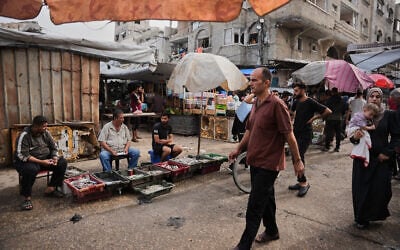Palestinians walk through a market in the Al-Shati refugee camp in Gaza City on October 14, 2026. (AP Photo/Abdel Kareem Hana)