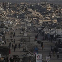 Palestinians walk along a street lined with buildings destroyed during the Israel-Hamas war in Gaza City October 14, 2026. (AP Photo/Jehad Alshrafi)