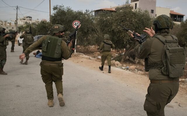Israeli soldiers move toward an injured Palestinian man following an alleged settler attack on Palestinians harvesting olives in the West Bank village of Abu Falah, October 16, 2026. (AP Photo/Leo Correa)
