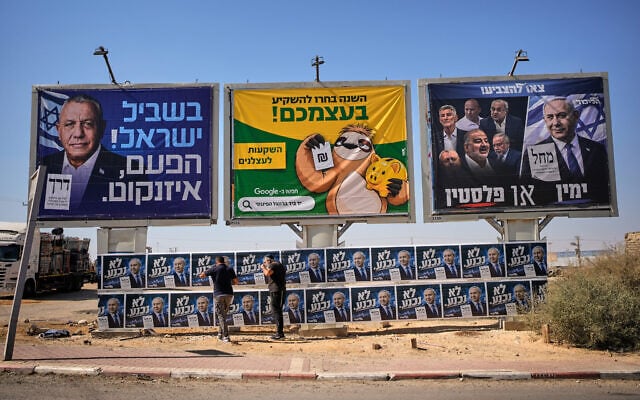 Likud activists hang campaign posters of Prime Minister Benjamin Netanyahu beside a billboard featuring opposition rival Gadi Eisenkot ahead of Israel’s general election in Dimona, southern Israel, October 21, 2026. (AP Photo/Ohad Zwigenberg)
