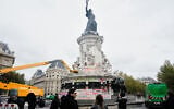 People watch and take photos of cleanup efforts after weekend protests over the cost of living turned into rioting and looting across France, in Paris, October 21, 2026. (AP Photo/Teresa Suarez)