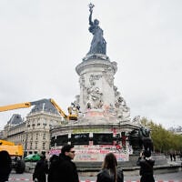 People watch and take photos of cleanup efforts after weekend protests over the cost of living turned into rioting and looting across France, in Paris, October 21, 2026. (AP Photo/Teresa Suarez)