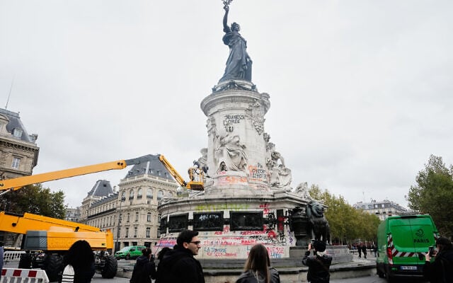 People watch and take photos of cleanup efforts after weekend protests over the cost of living turned into rioting and looting across France, in Paris, October 21, 2026. (AP Photo/Teresa Suarez)