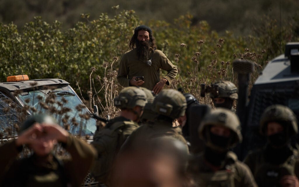 An settler overlooks members of Israeli forces blocking a road preventing Palestinians from reaching groves to harvest olives in the West Bank town of Turmus Ayya, October 21, 2026. (AP Photo/Leo Correa)