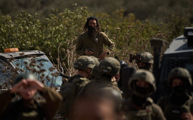 An settler overlooks members of Israeli forces blocking a road preventing Palestinians from reaching groves to harvest olives in the West Bank town of Turmus Ayya, October 21, 2026. (AP Photo/Leo Correa)