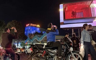 People take pictures of a billboard installation featuring an actor portraying US President Donald Trump behind bars in a mock prison cell in Tajrish Square in Tehran, October 21, 2026. (AP Photo/Vahid Salemi)