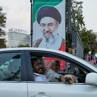 A man and a woman ride in a car with a dog past a portrait of Iran’s Supreme Leader Mojtaba Khamenei in Tehran, Iran, October 21, 2026. (AP Photo/Vahid Salemi)
