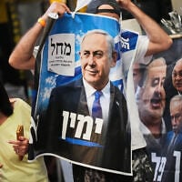 A Likud Party activist holds a campaign banner featuring Prime Minister Benjamin Netanyahu at a market in Tel Aviv, October 22, 2026, ahead of the election. (AP Photo/Ariel Schalit)