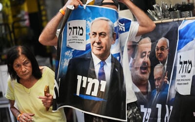 A Likud Party activist holds a campaign banner featuring Prime Minister Benjamin Netanyahu at a market in Tel Aviv, October 22, 2026, ahead of the election. (AP Photo/Ariel Schalit) A Likud Party activist holds a campaign banner featuring Prime Minister Benjamin Netanyahu at a market in Tel Aviv, October 22, 2026, ahead of the election. (AP Photo/Ariel Schalit)