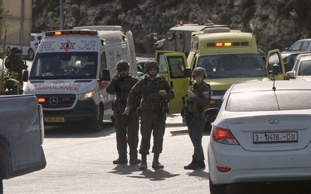 Israeli soldiers and emergency personnel gather near ambulances following a shooting attack carried out by Palestinian gunmen at a junction near Hebron in the West Bank, October 23, 2026. (AP Photo/Mahmoud Illean)