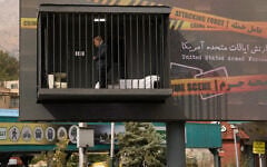 An actor portraying US President Donald Trump walks behind bars in a billboard installation resembling a prison cell in Tajrish Square in Tehran, Iran, October 23, 2026. (AP Photo/Vahid Salemi)