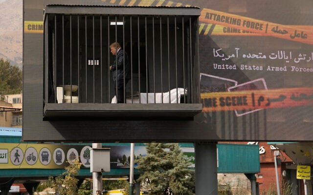 An actor portraying US President Donald Trump walks behind bars in a billboard installation resembling a prison cell in Tajrish Square in Tehran, Iran, October 23, 2026. (AP Photo/Vahid Salemi)