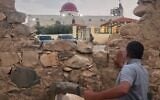 A man looks through a gap in a stone wall toward a Greek Orthodox church where gunmen opened fire during a funeral hours earlier in Hamoud village, in Jordan’s Karak governorate, October 23, 2026. (AP Photo)