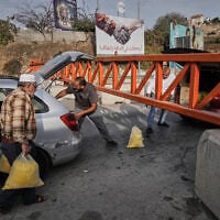 Palestinians transport bags of semolina past a military gate closed to vehicles during an Israeli army operation in Hebron, in the West Bank, October 24, 2026, a day after two IDF soldiers were killed by Palestinian gunmen in the area. (AP Photo/Mahmoud Illean)
