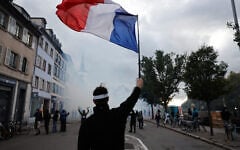 A protester holds a French flag during a demonstration against rising living costs in Strasbourg, France, October 24, 2026. (AP Photo/Jean-Francois Badias)